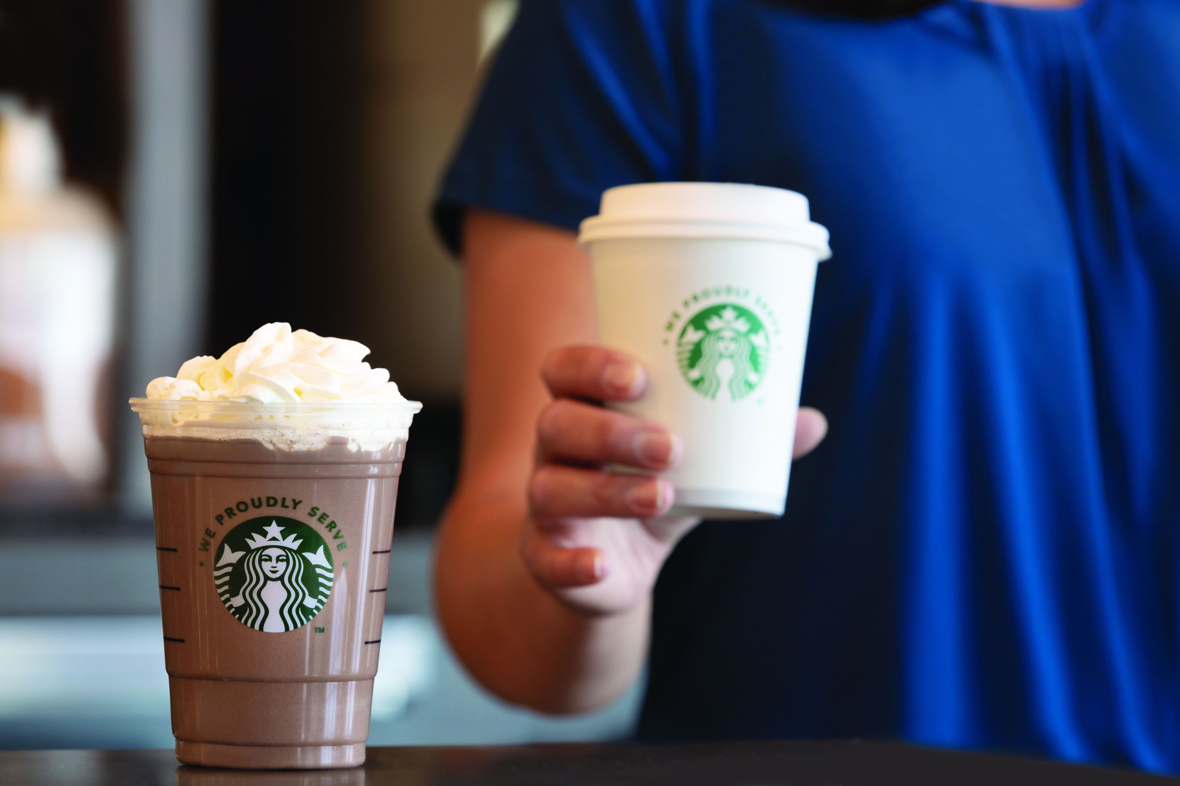 A Starbucks cup with whipped cream and a Starbucks cup without whipped cream.
