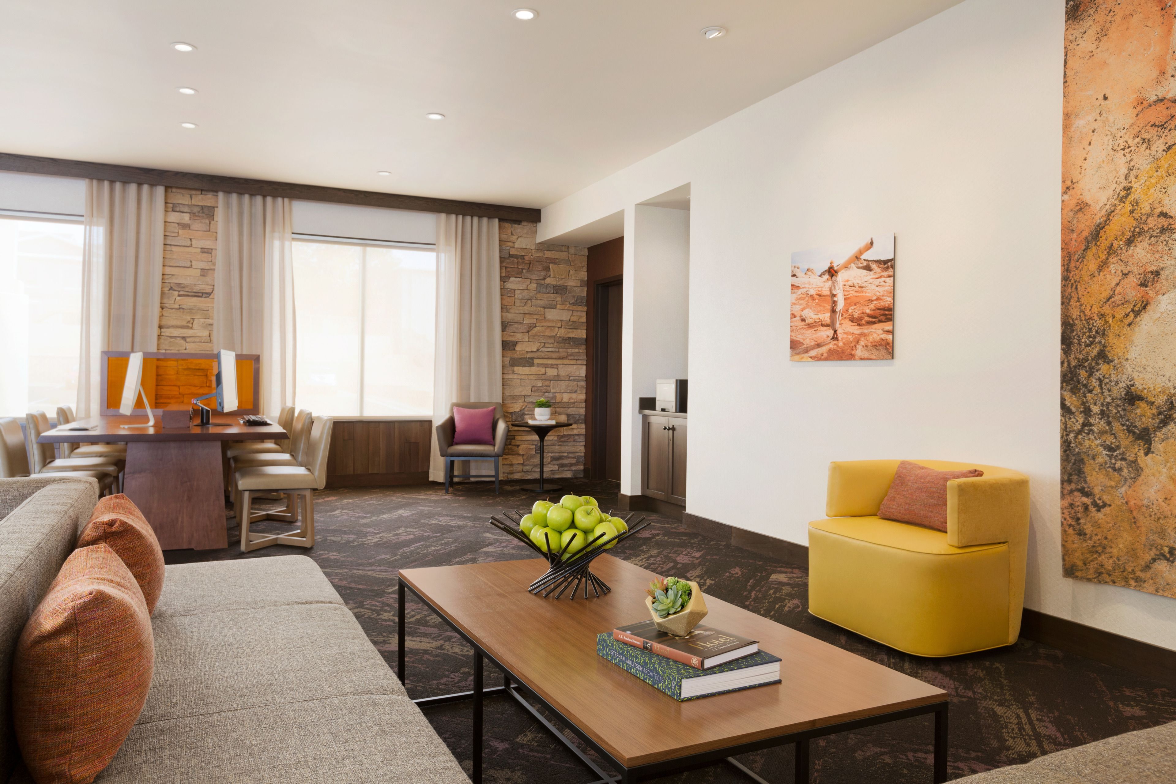 Una sala moderna con un sofá, un sillón amarillo y una zona de comedor con mesa y sillas.