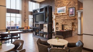 A modern lounge area with a fireplace, a large entertainment unit, and comfortable seating. - Hyatt Place Page Lake Powell (Page)