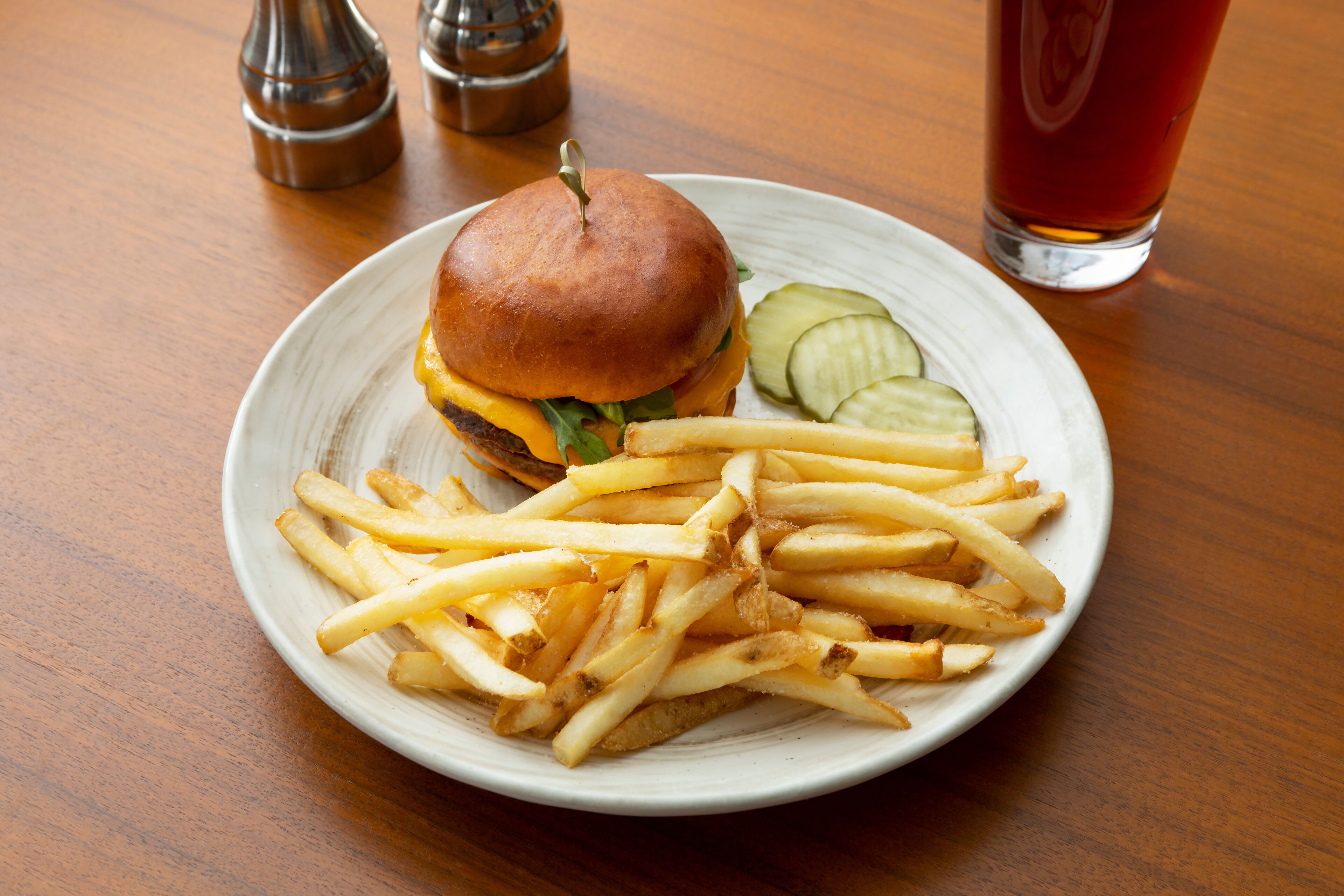 A plate with a burger and fries on a wooden table.