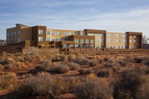 A multi-story building with a flat roof and large windows, surrounded by dry, bushy terrain. - Hyatt Place Page Lake Powell (Page)