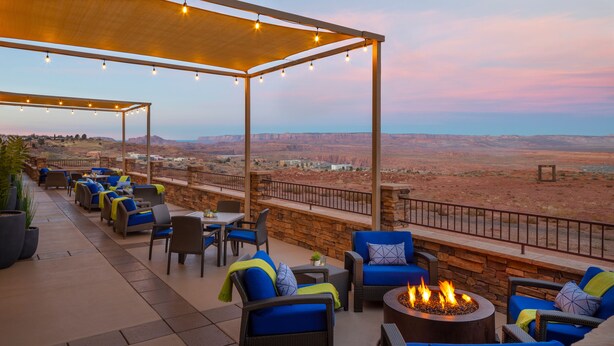 An outdoor patio with wicker furniture, a fire pit, and a view of the desert landscape. - Hyatt Place Page Lake Powell (Page)