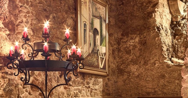 Un muro de piedra con un cuadro enmarco y un candelabro con velas encendidas.