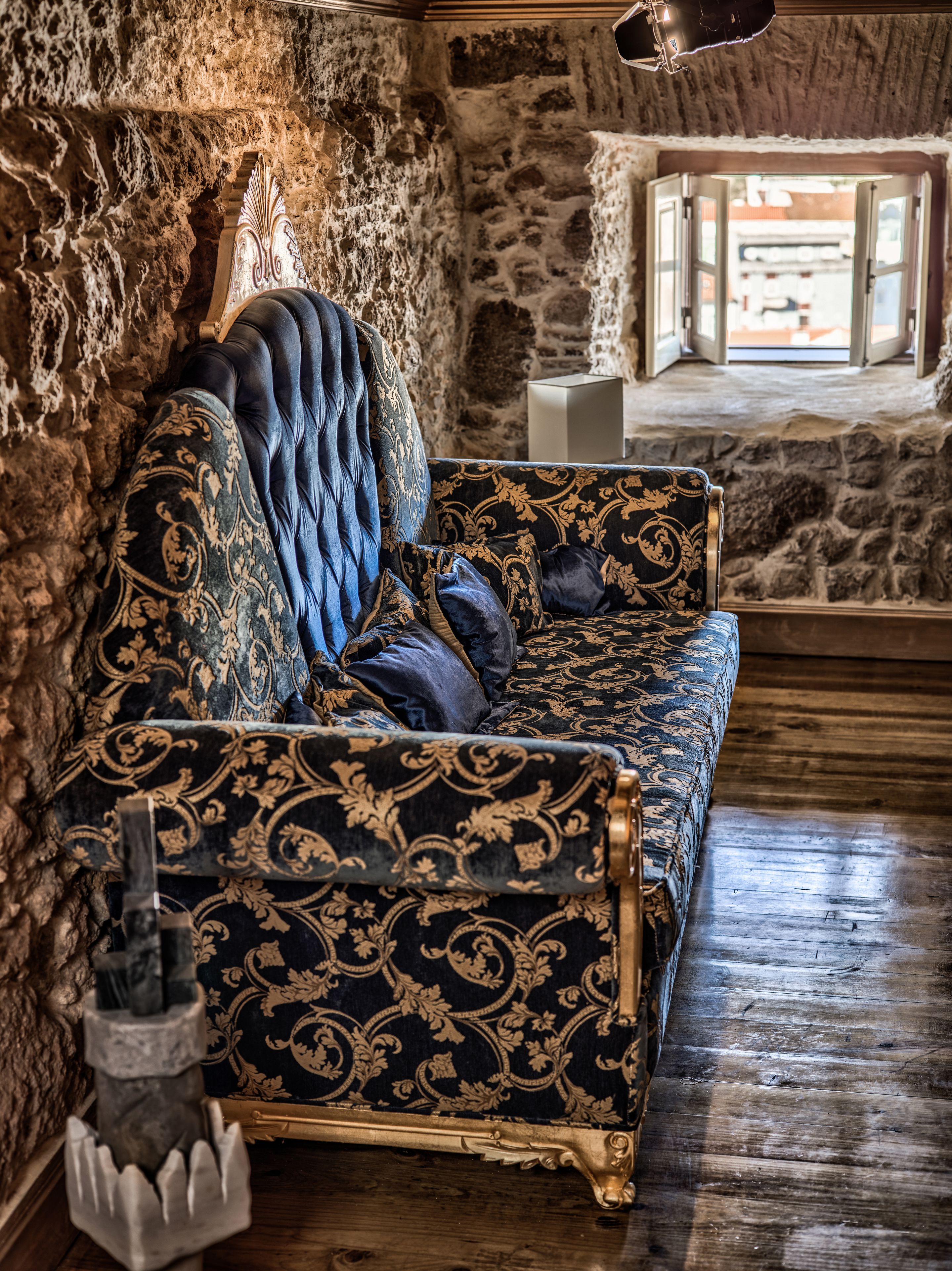 Una habitación con pared de piedra, un sofá estampado y suelo de madera.