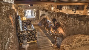 A stone-walled room with a wooden bench, a table with candles, and a view through a window. - Solar Antigo Luxury Spa Coimbra (Coimbra)