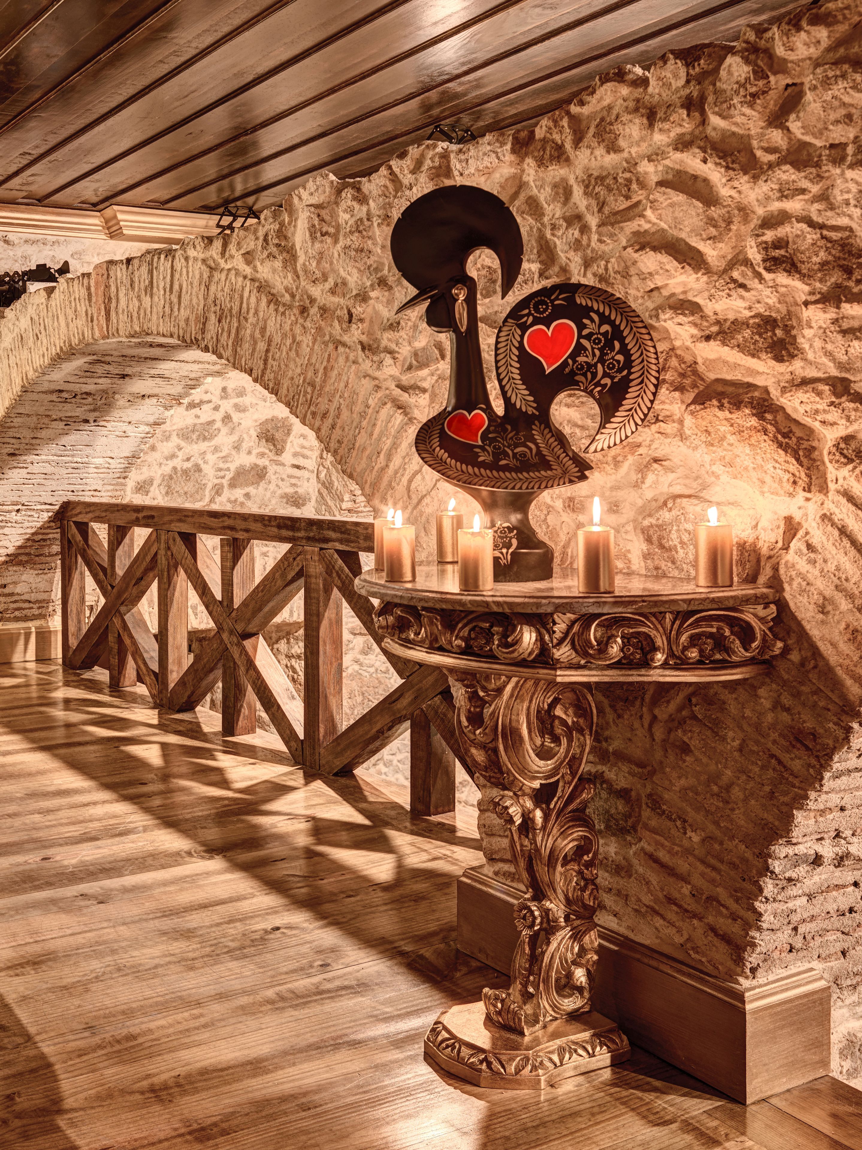 Une pièce aux murs de pierre, avec une table en bois et des bougies.