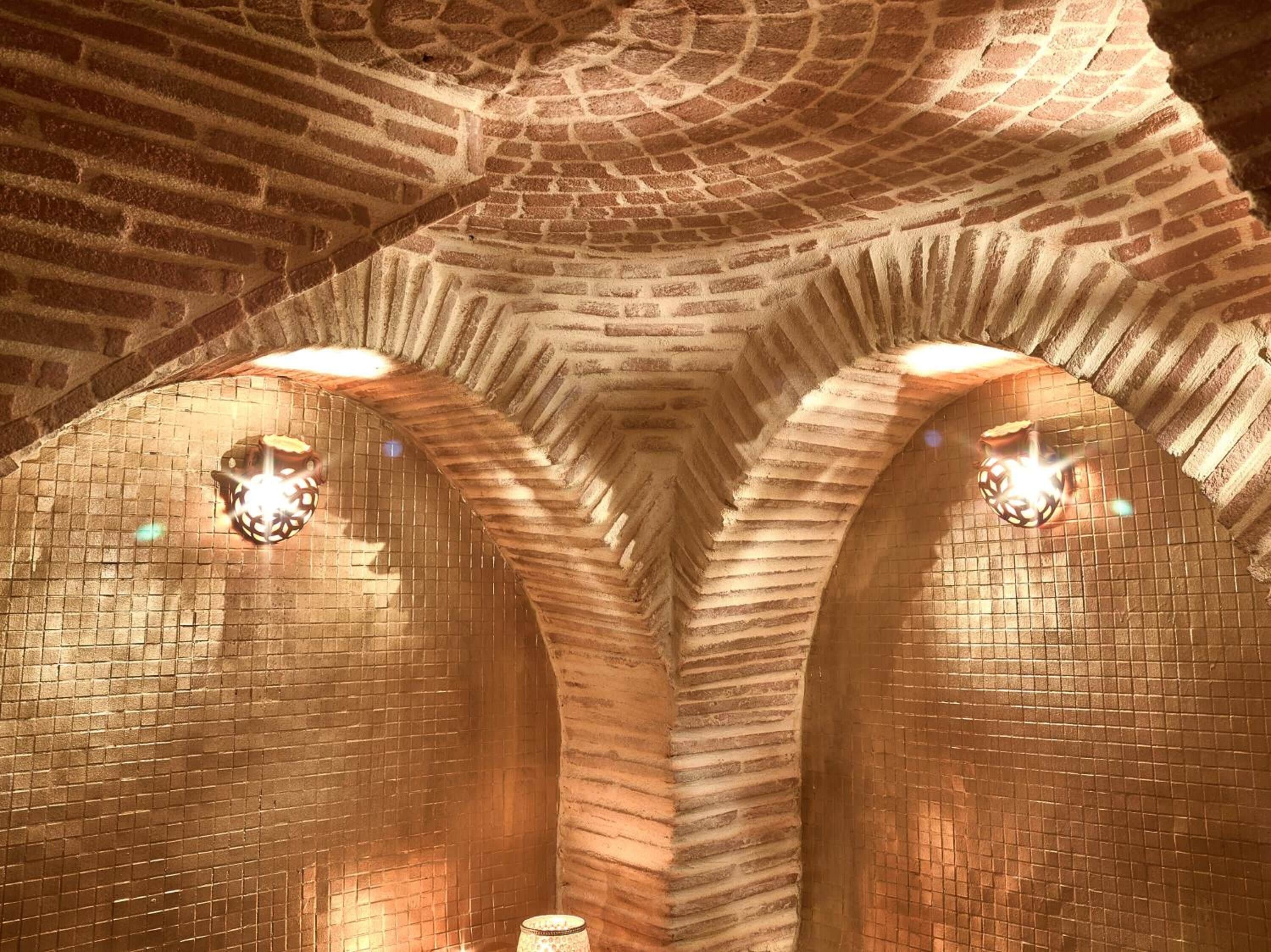 A vaulted brick ceiling with two wall-mounted light fixtures.