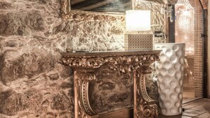 A stone-walled room with a marble vanity, ornate mirror, and a white vase. - Solar Antigo Luxury Spa Coimbra (Coimbra)