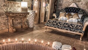 A luxurious bathroom with a marble wall, a large mirror, an ornate vanity, a bathtub with green water, and a plush bed with multiple pillows. - Solar Antigo Luxury Spa Coimbra (Coimbra)