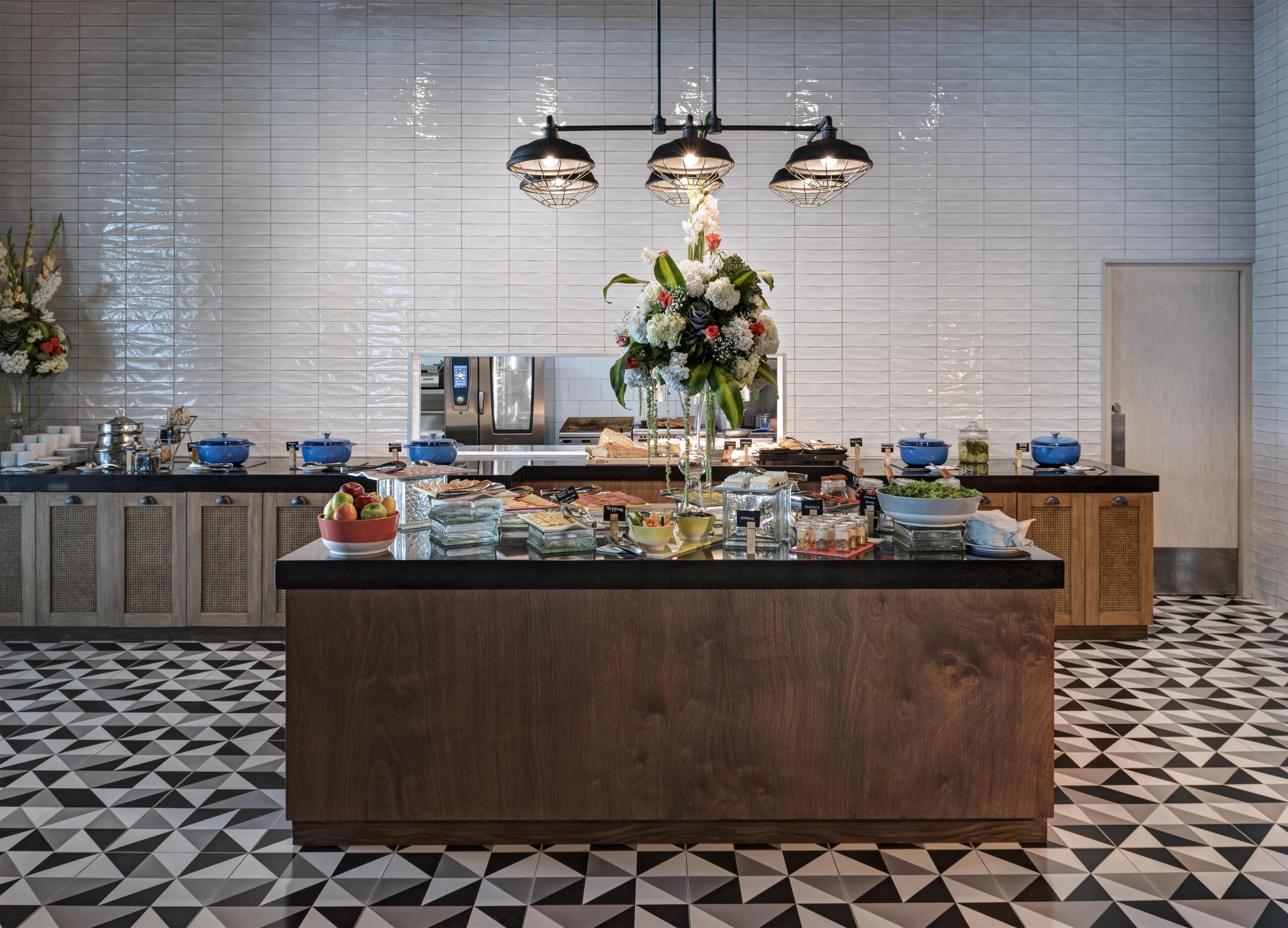 Una cocina moderna con una isla central, equipada con diversos alimentos y un refrigerador al fondo.