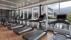 Une salle de sport équipée de tapis de course, de vélos d’exercice et d’un appareil d’aviron.