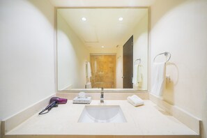 Une salle de bain avec un grand miroir, un lavabo et un porte-serviettes.