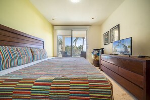 Une chambre à coucher avec un grand lit, une commode en bois et un téléviseur.