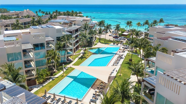 A resort with multiple swimming pools, palm trees, and a view of the ocean. - Castillo de Arena by NAS (Playa del Carmen)