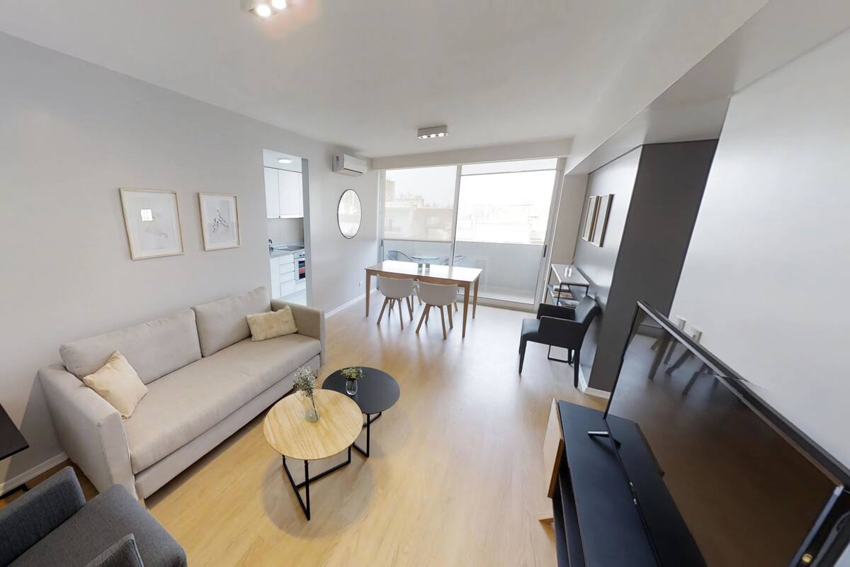 A modern living room with a sofa, coffee table, and a dining area with chairs.