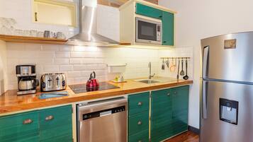 Una cocina moderna con un refrigerador de acero inoxidable, un microondas, un lavavajillas y una tetera.