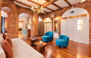 A spacious living area with a brick fireplace, wooden beams, and a chandelier. - Old Town Quito Suites, Apartments & Boutique hotel (Quito)