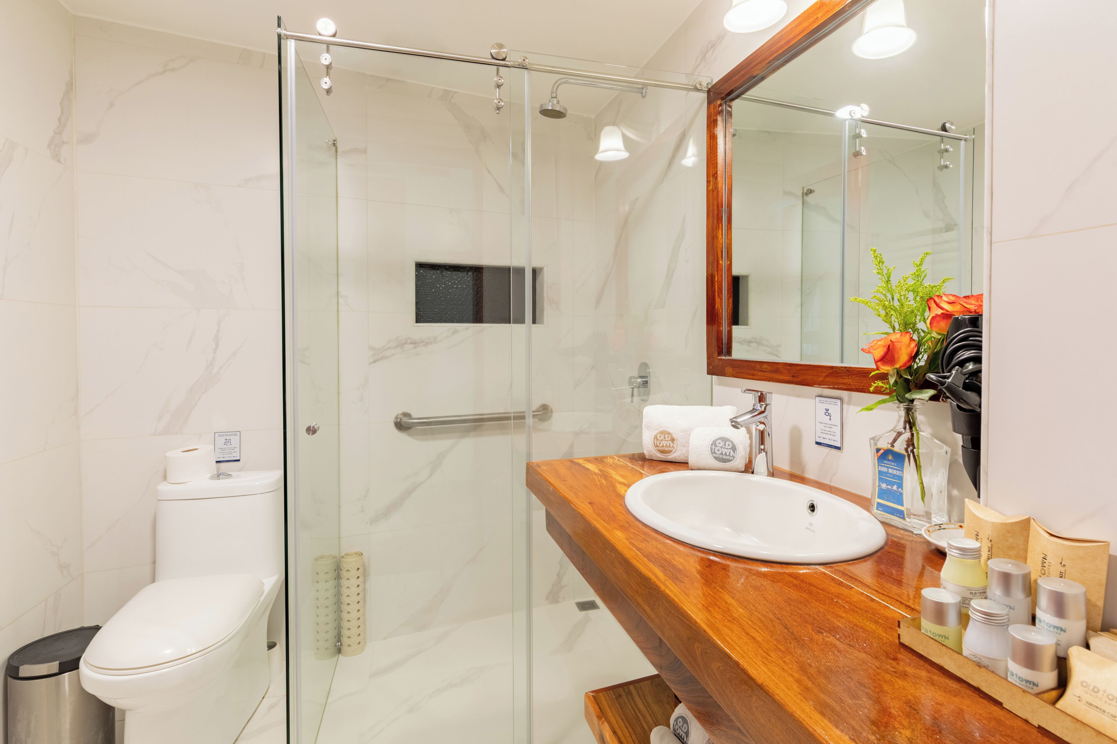 A modern bathroom with a glass shower enclosure, a wooden vanity with a sink, and a mirror.