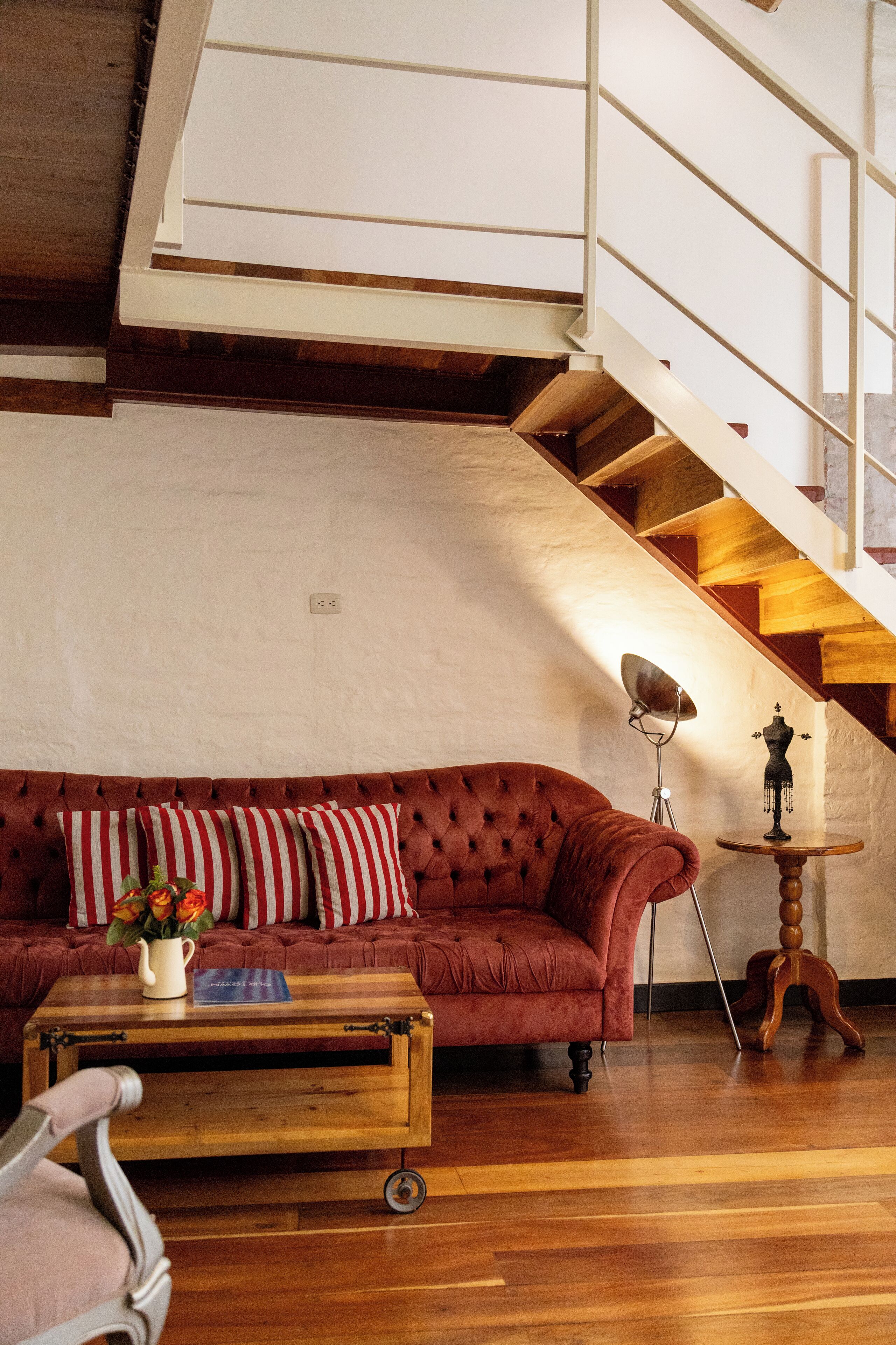 A living room with a red sofa, a wooden coffee table, a lamp, and a staircase.