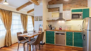 Una cocina con vigas de madera, una mesa de comedor con sillas, microondas y lavavajillas.