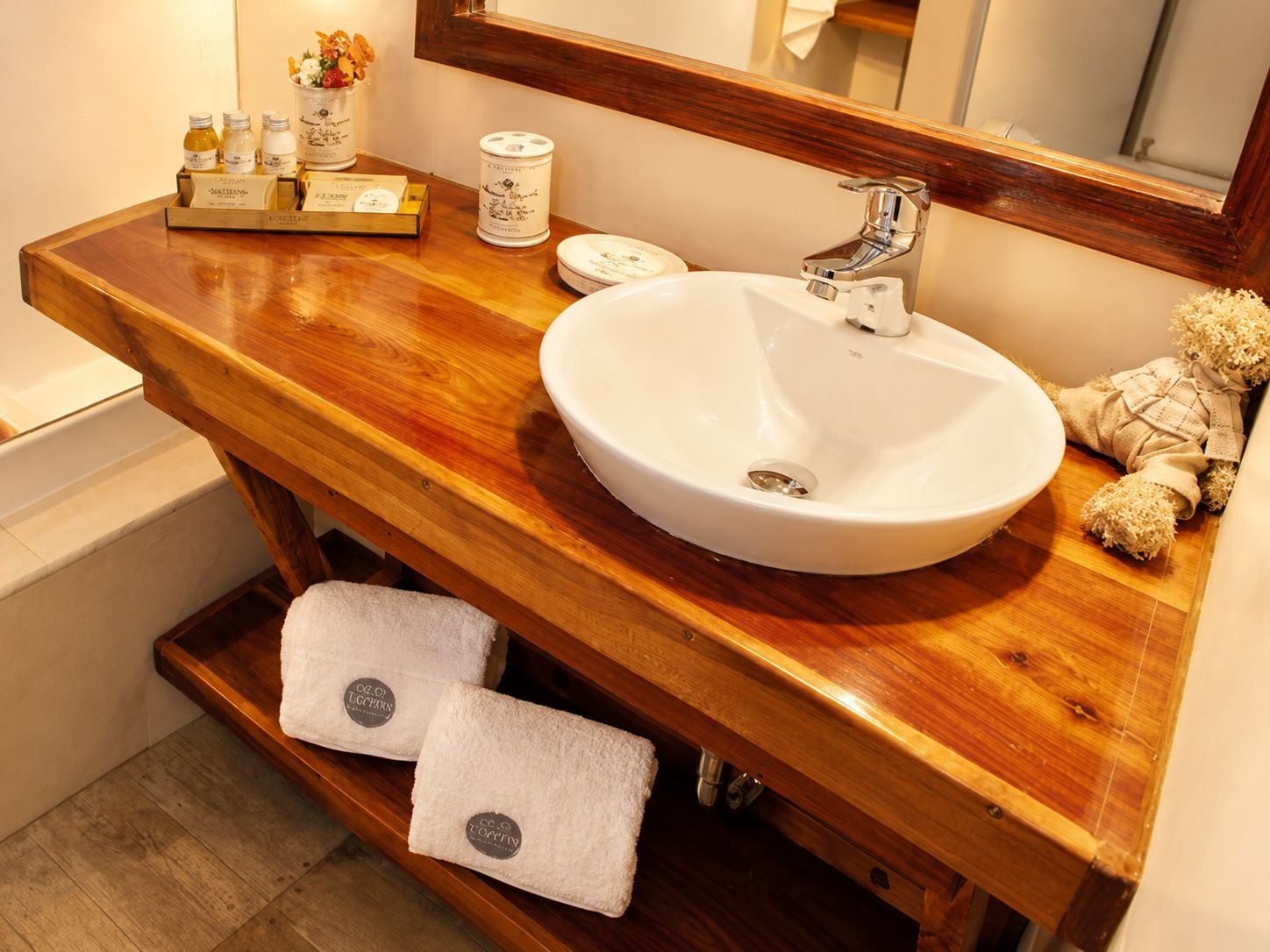 A bathroom with a wooden vanity, a white sink, a mirror, and two towels.