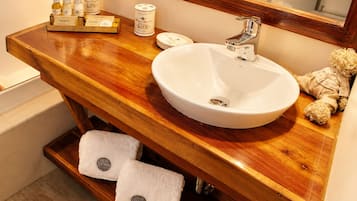 Un baño con tocador de madera, un lavamanos blanco, un espejo y dos toallas.