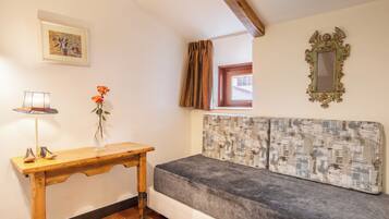 Una habitación acogedora con una mesa de madera, un florero con flores, un cabecero estampado y un espejo enmarco.