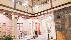 A courtyard with stone flooring, a table with chairs, potted plants, and a wooden door. - Old Town Quito Suites, Apartments & Boutique hotel (Quito)