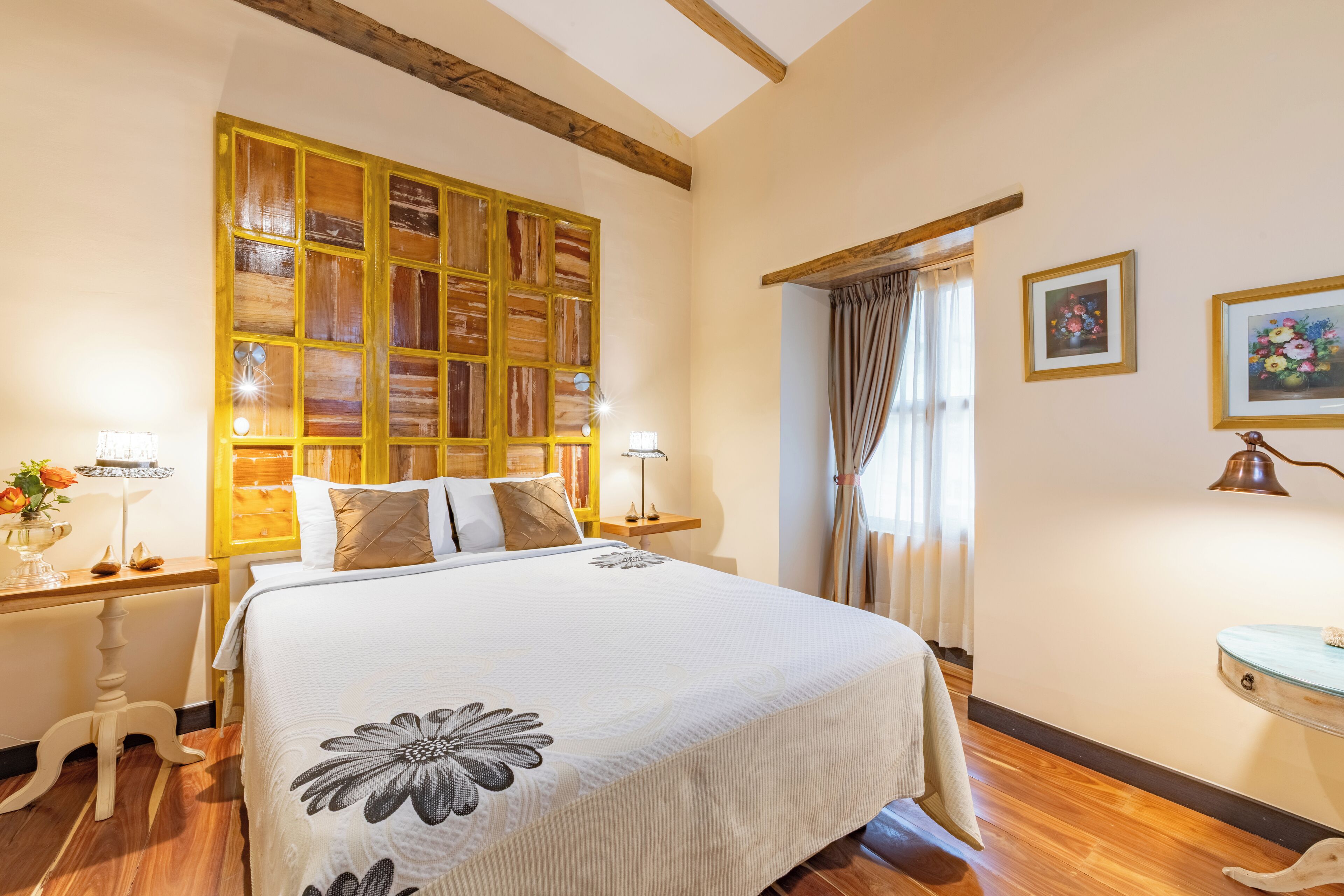 Une chambre à coucher avec un grand lit, une tête de lit en bois, des tables de chevet et une petite table de nuit.