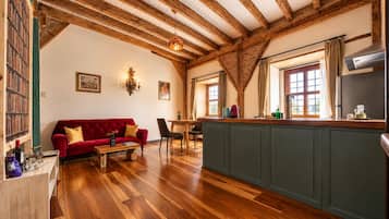 A spacious living area with a red sofa, wooden flooring, and exposed wooden beams.