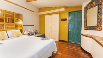 A bedroom with a bed, wooden headboard, a wardrobe, a mirror, and a door.