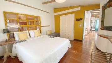 A bedroom with a large bed, wooden beams, a white wardrobe, and a mirror with a decorative frame.