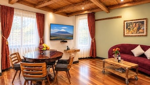 A room with a wooden dining table, chairs, a sofa, a TV on the wall, and a painting. - Old Town Quito Suites, Apartments & Boutique hotel (Quito)