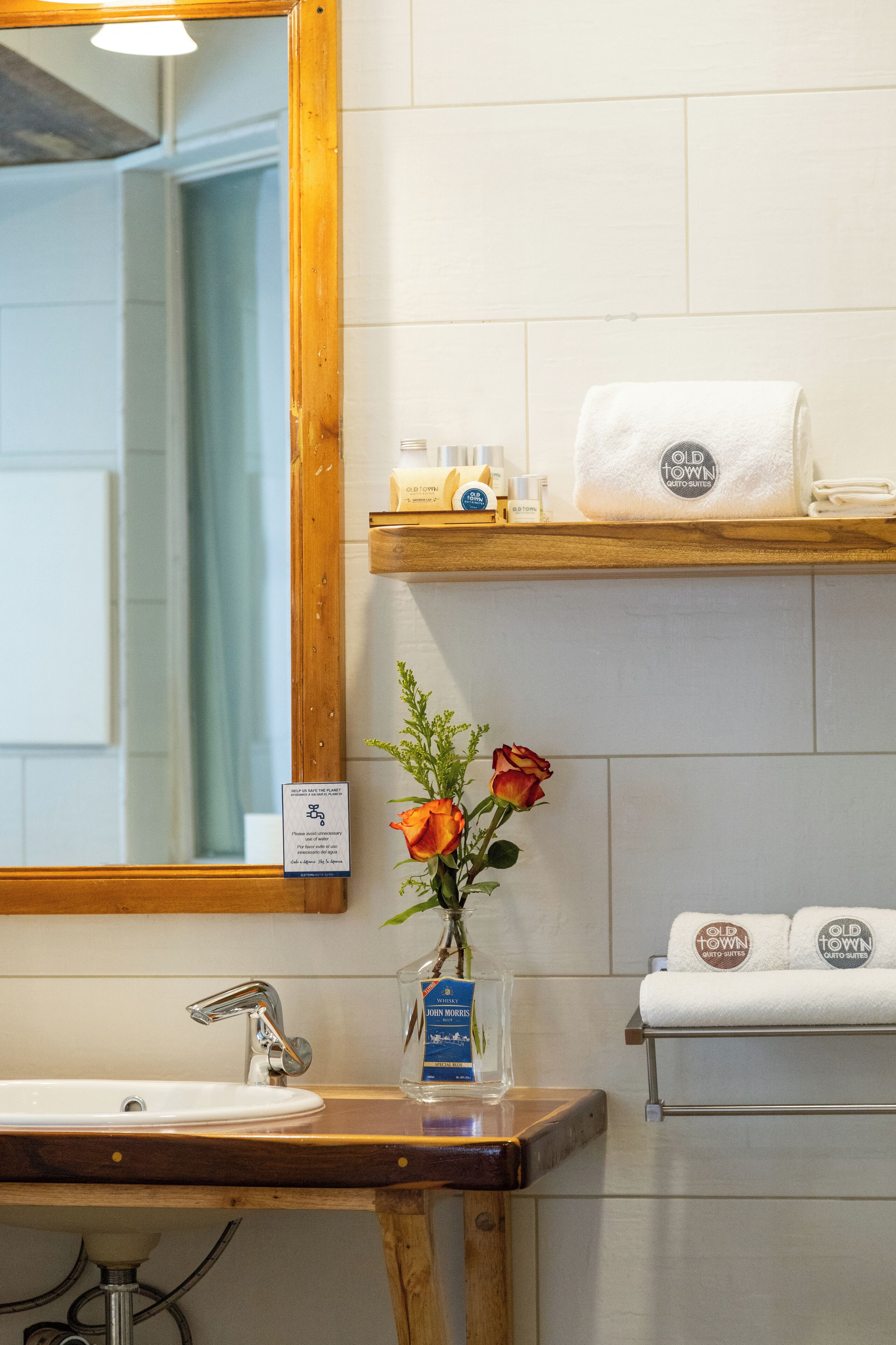 Un bagno con un mobile vanitario in legno, uno specchio, un lavandino, un porta asciugamani e uno scaffale con articoli da toilette.