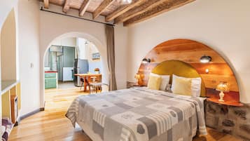 A bedroom with a large bed, wooden headboard, and a small table with a lamp.