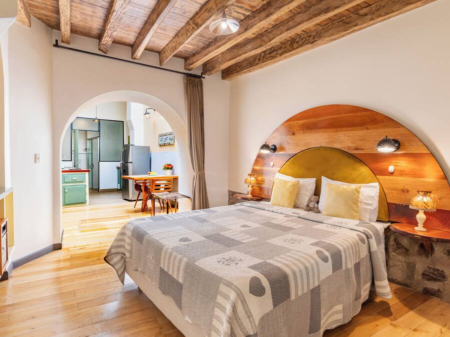 Un dormitorio con una cama grande, cabecera de madera y una mesita de noche con lámpara.