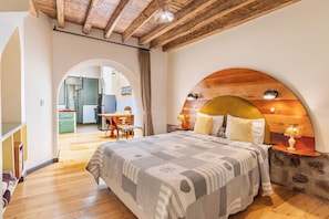A bedroom with a large bed, wooden headboard, and a small table with a lamp. - Old Town Quito Suites, Apartments & Boutique hotel (Quito)