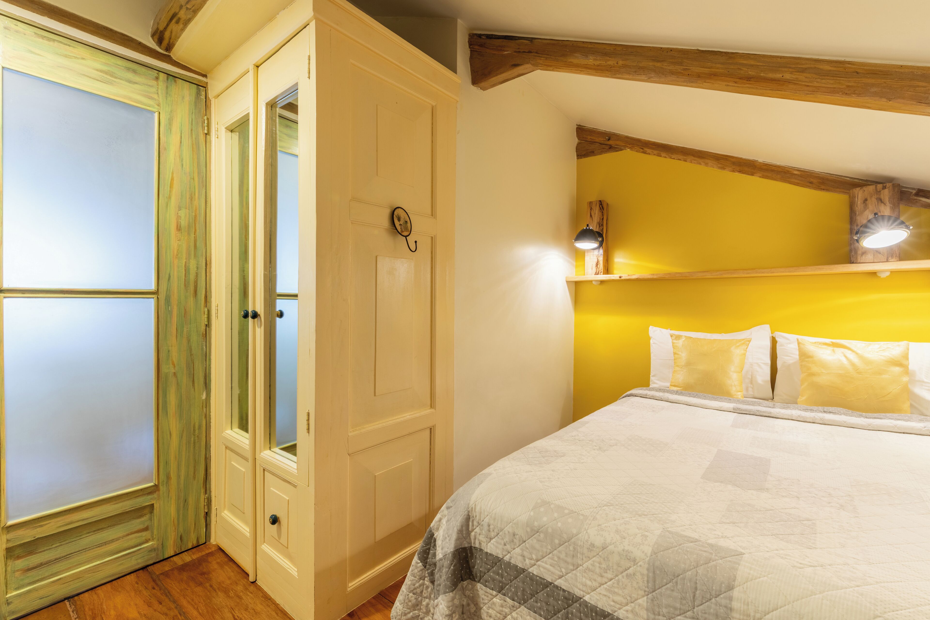 Ein Schlafzimmer mit einem Bett, einem Kleiderschrank und einem Regal mit einer Lampe.