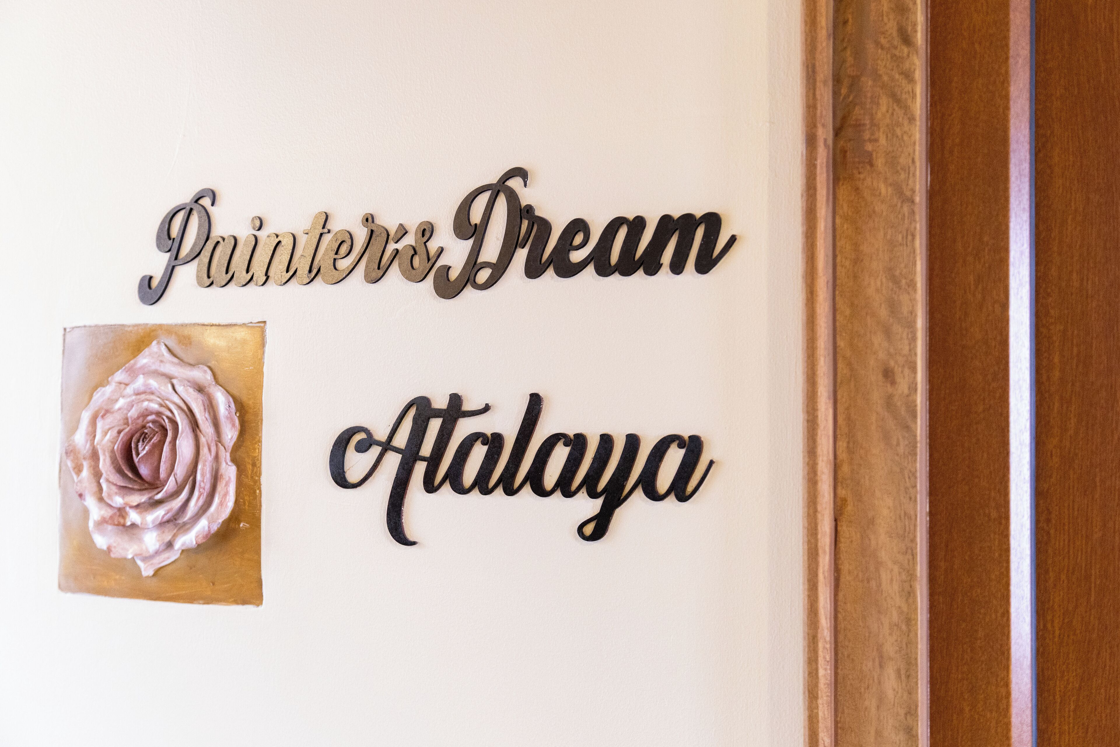 A wall with the text 'Painters Dream Atalaya' and a framed picture of a rose.