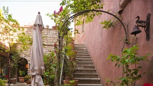 A stone staircase with potted plants and a table with a canopy. - Hotel Elimo (Erice)