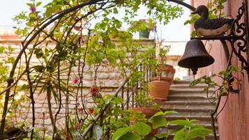 A narrow staircase with potted plants and flowers, leading to a building entrance.