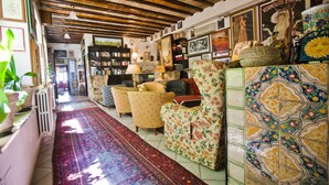 A cozy living room with a patterned rug, floral armchairs, and a tiled wall. - Hotel Elimo (Erice)