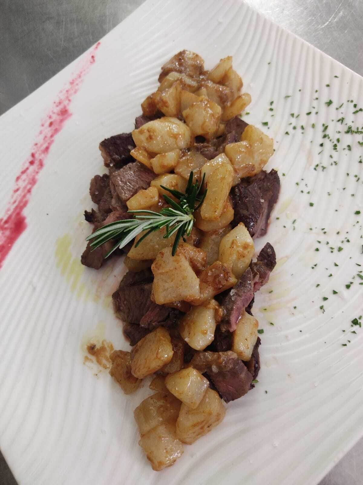 A plate of food with steak and potatoes, garnished with rosemary.