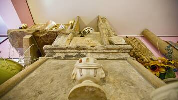 A stone structure with a carved figure, possibly a tomb or monument, with various artifacts and decorations around it.