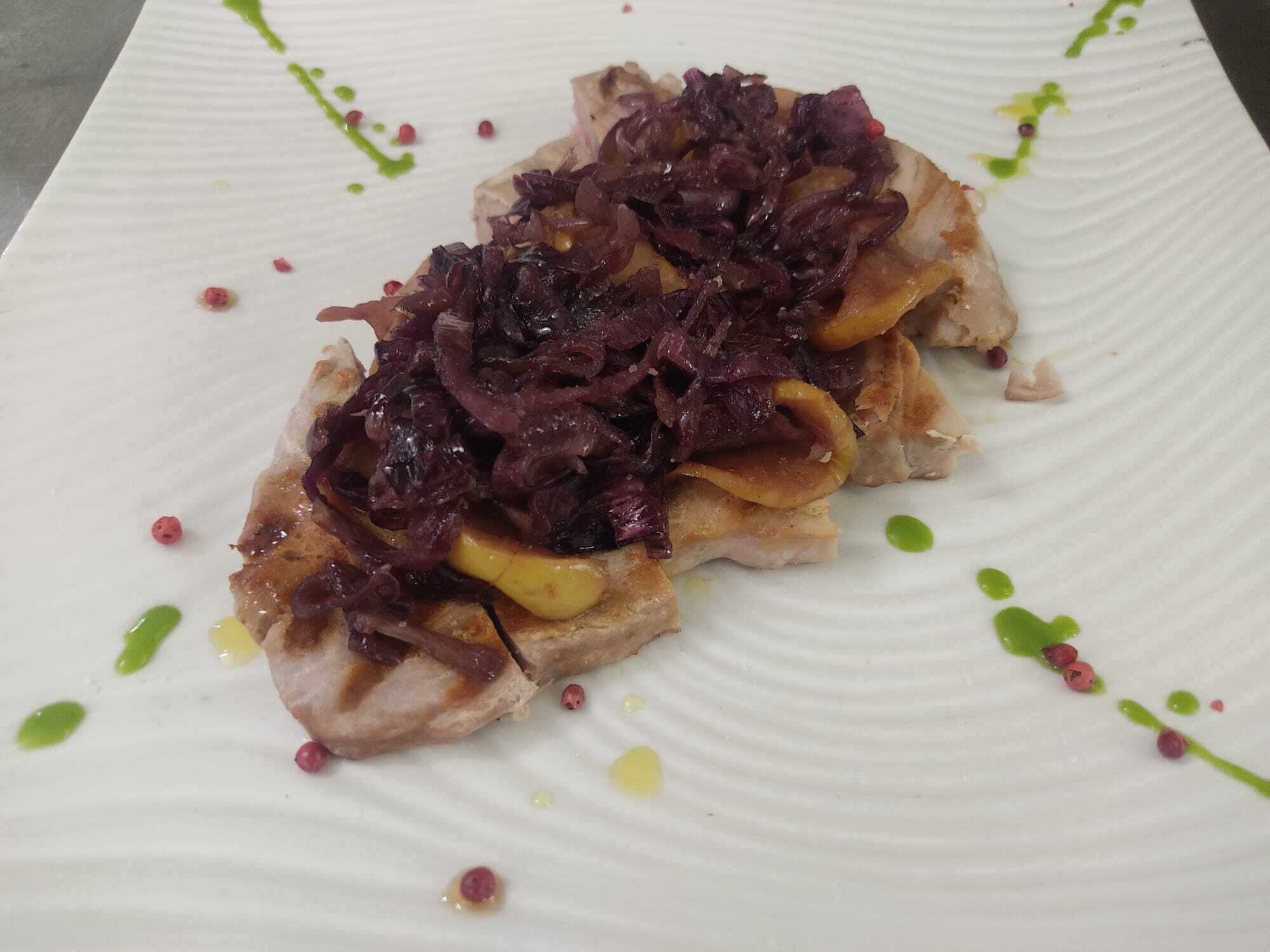 A plate with a dish topped with red cabbage and slices of apple, garnished with green and yellow sauces.