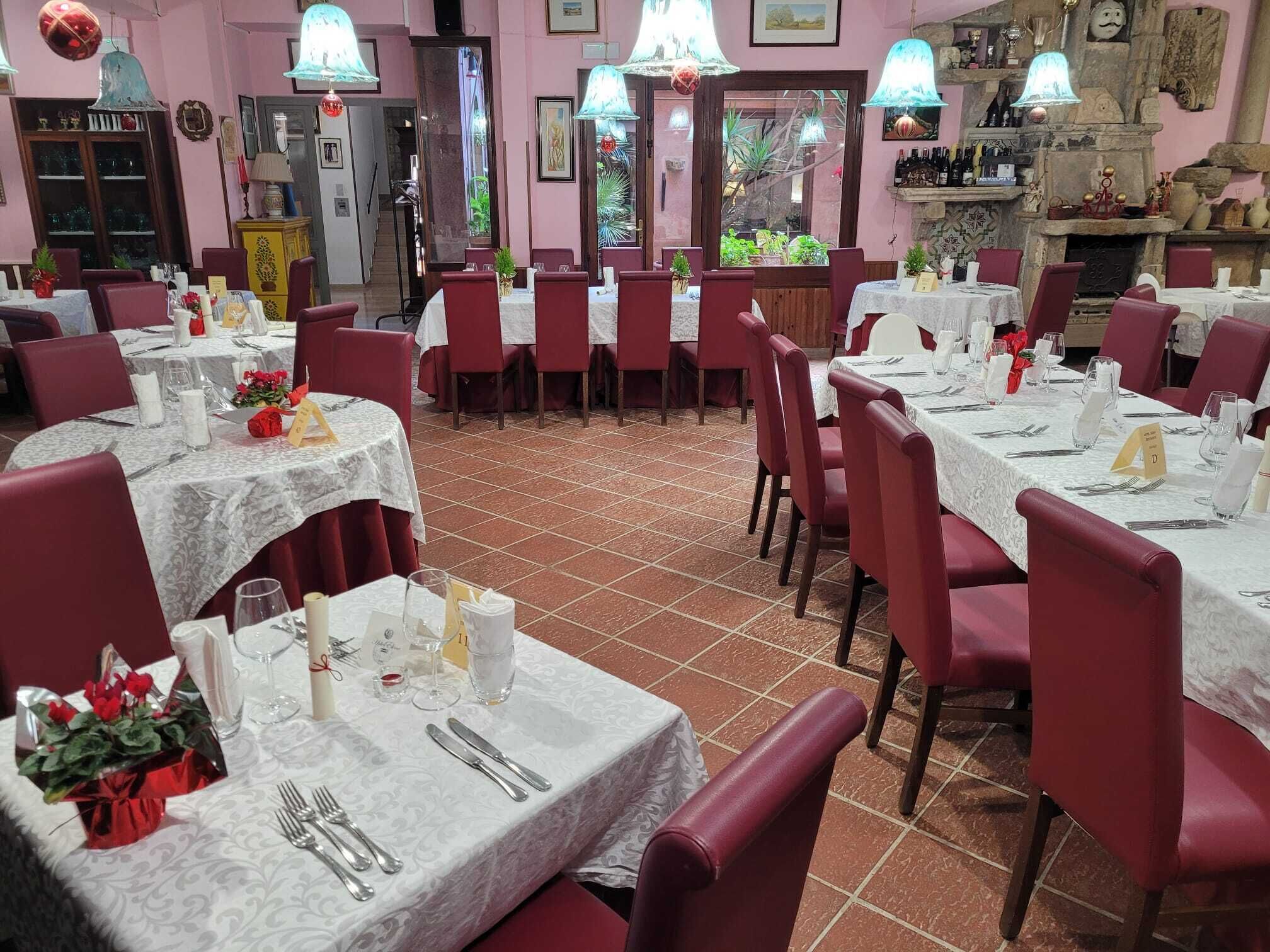 Ein Restaurant mit mehreren Tischen, gedeckt für das Essen, mit weißen Tischdecken und roten Stühlen.
