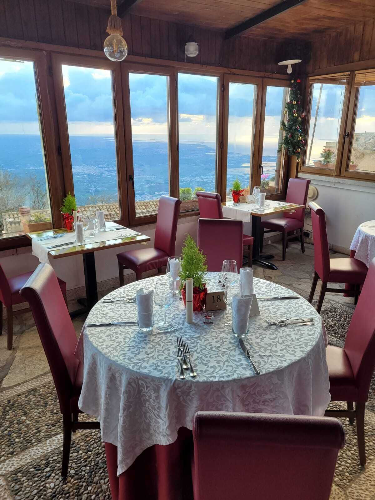 A restaurant with round tables, red chairs, and a view of the sea.
