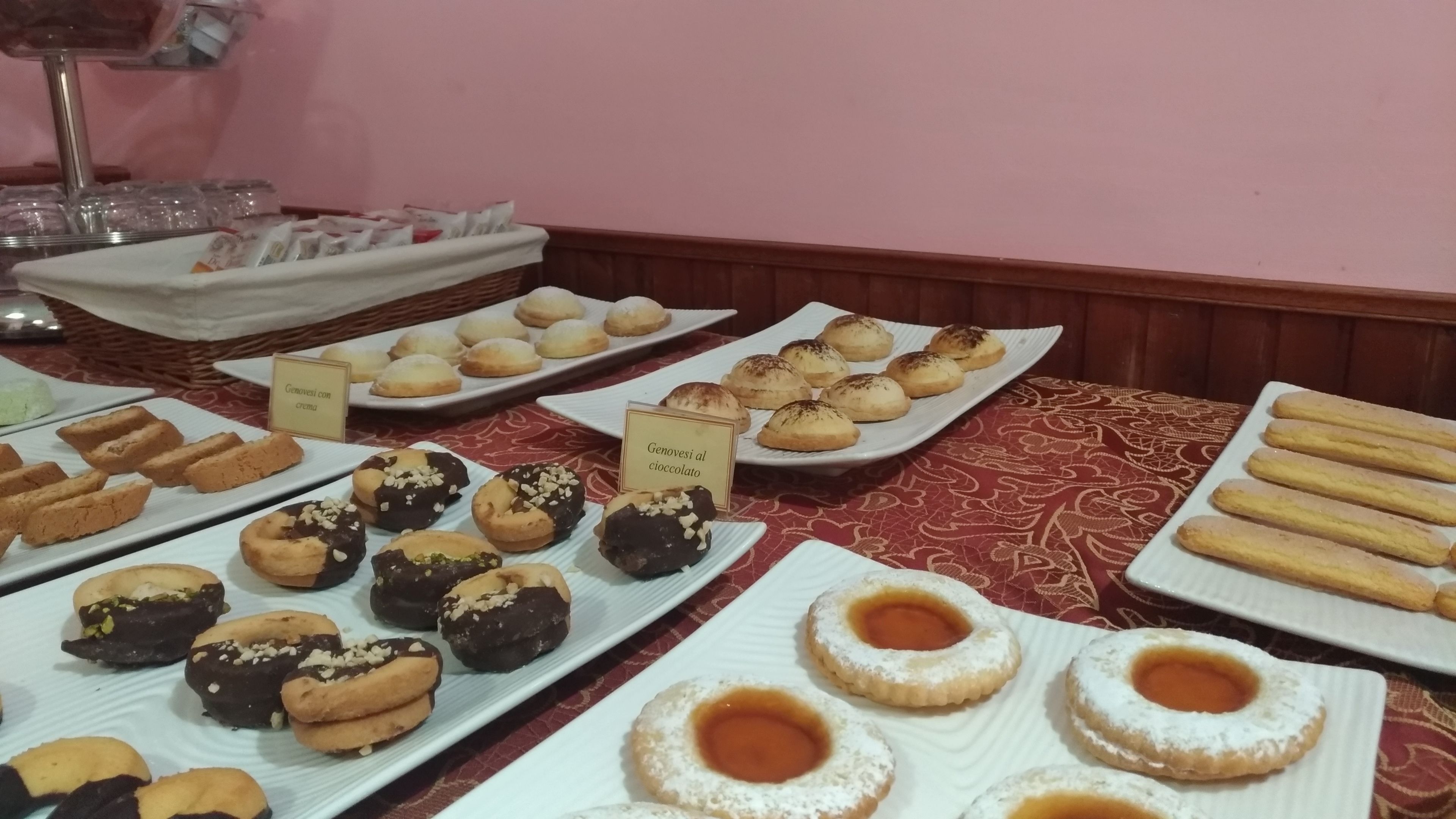 A buffet table with various pastries and desserts, including croissants and cookies, arranged on white plates.