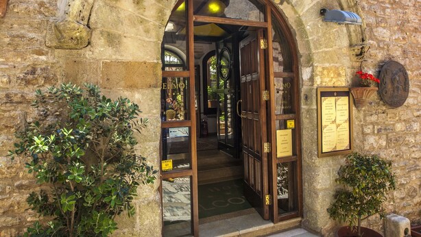 An entrance with a stone archway, potted plants, and a cobblestone path. - Hotel Elimo (Erice)