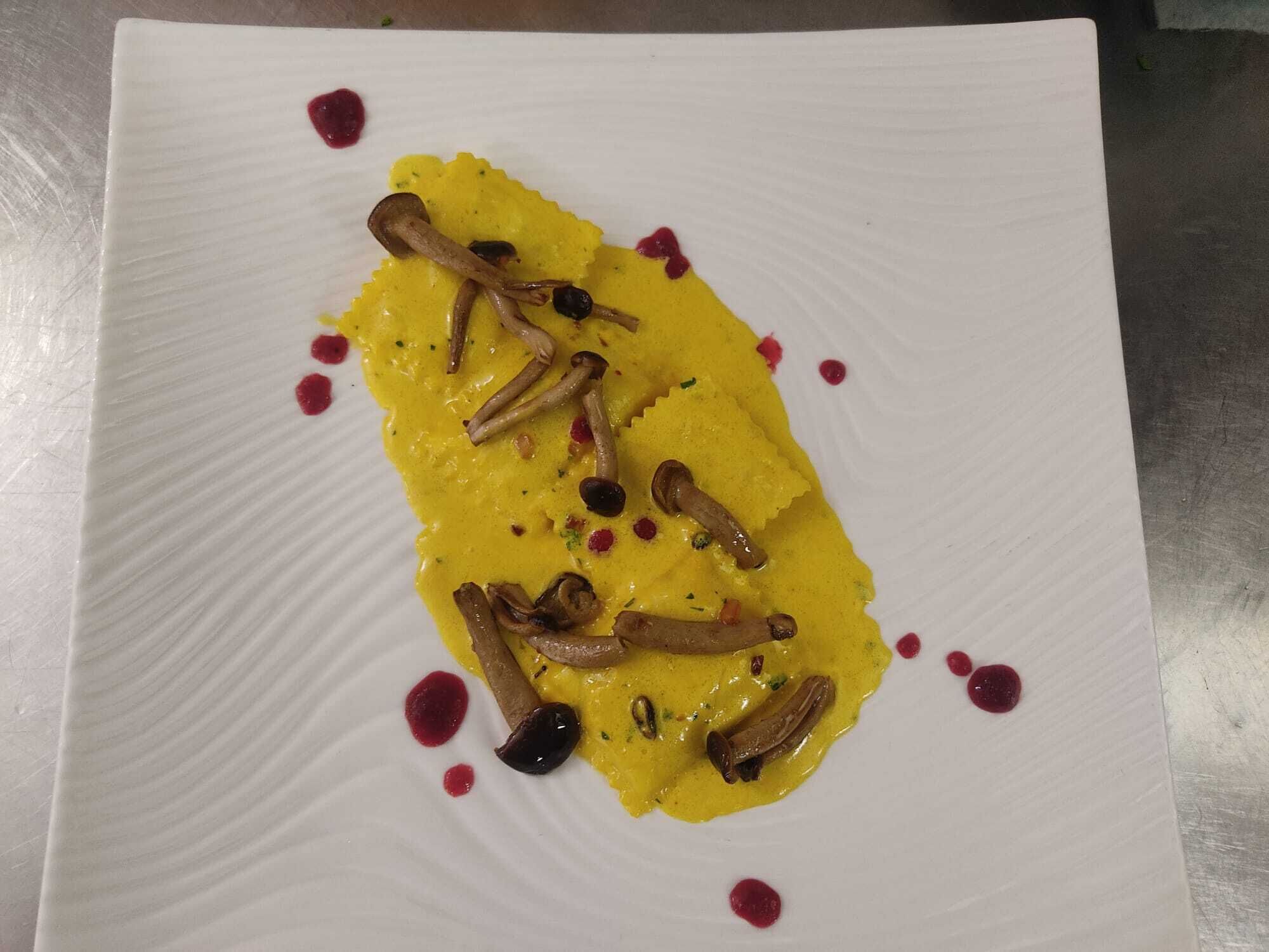 A square white plate with a yellow sauce, mushrooms, and red dots.